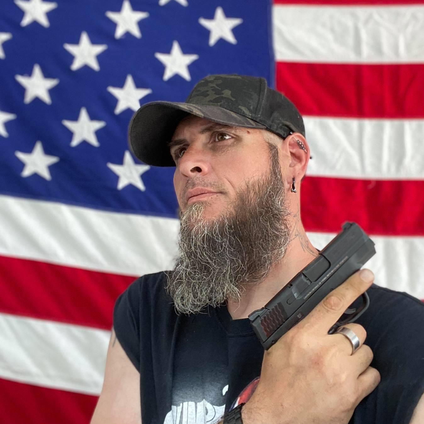 man holding a gun in front of an american flag