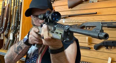 a man pointing a gun in a gun store