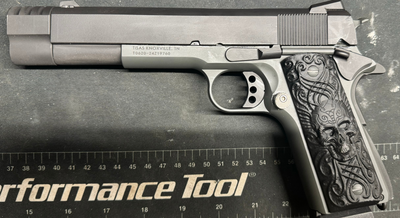 a silver gun with a black embossed skull on it