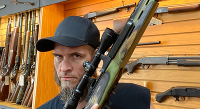a man holding up a gun in a gun store