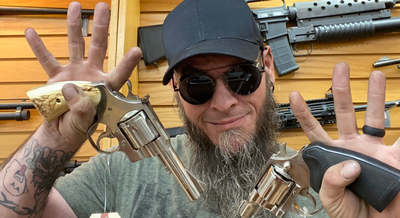 a man holding up 2 small guns and smiling