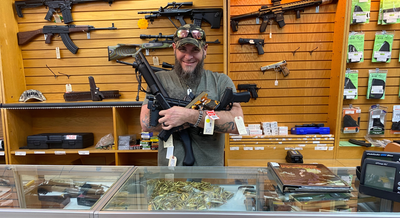a man holding 5 guns in his arms at a gun store