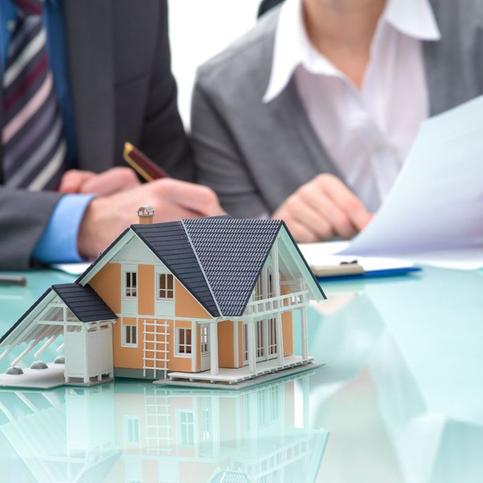 Two realtors review documents behind model home