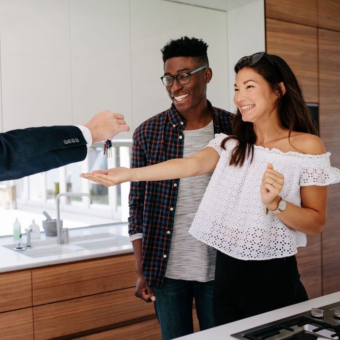 Realtor hands keys to excited and happy new homeowner couple