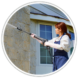 woman power washing the outside of a home. 