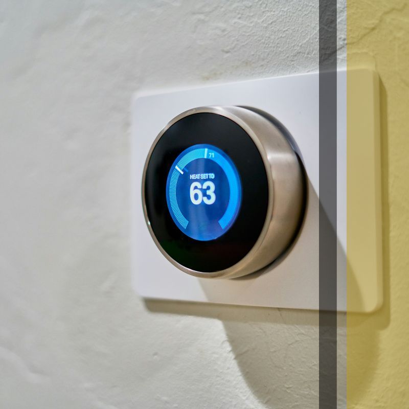 A modern digital thermostat displaying a temperature of 63 degrees Fahrenheit.