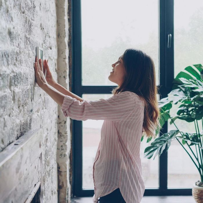 Image of a woman installing a new thermostat in her home