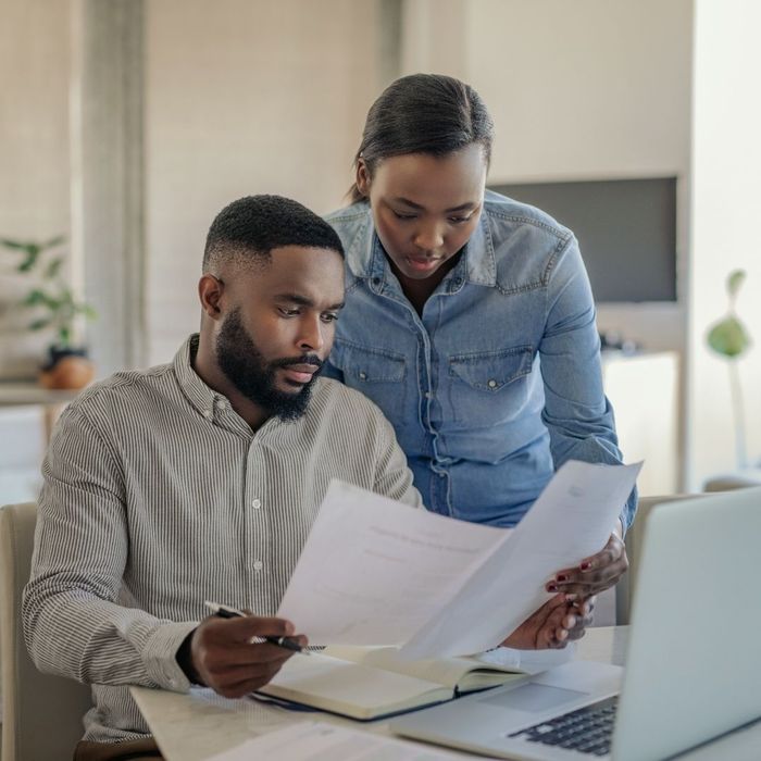 A man and a woman looking at documents together at a table with a laptop.