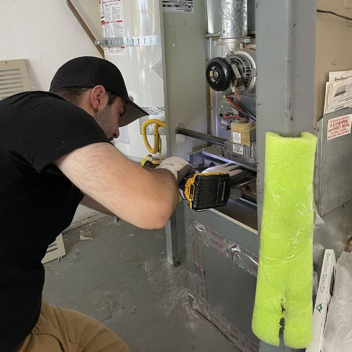A Beaver Heating & Air tech repairing a home's furnace.