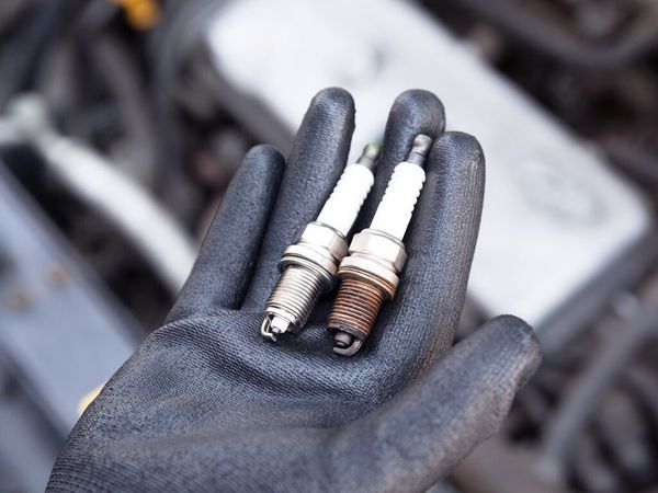 photo of mechanic holding old and new spark plugs