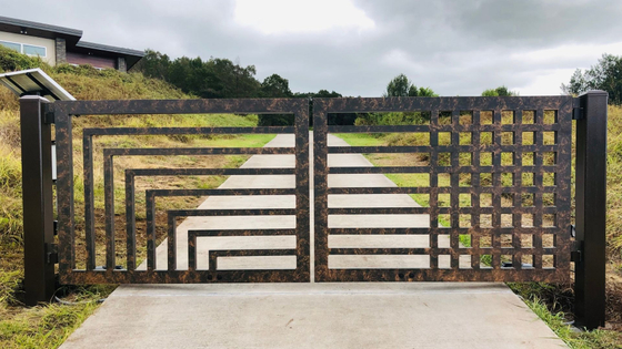 Modern brown metal driveway gate with geometric patterns. Modern brown metal driveway gate with geometric patterns.