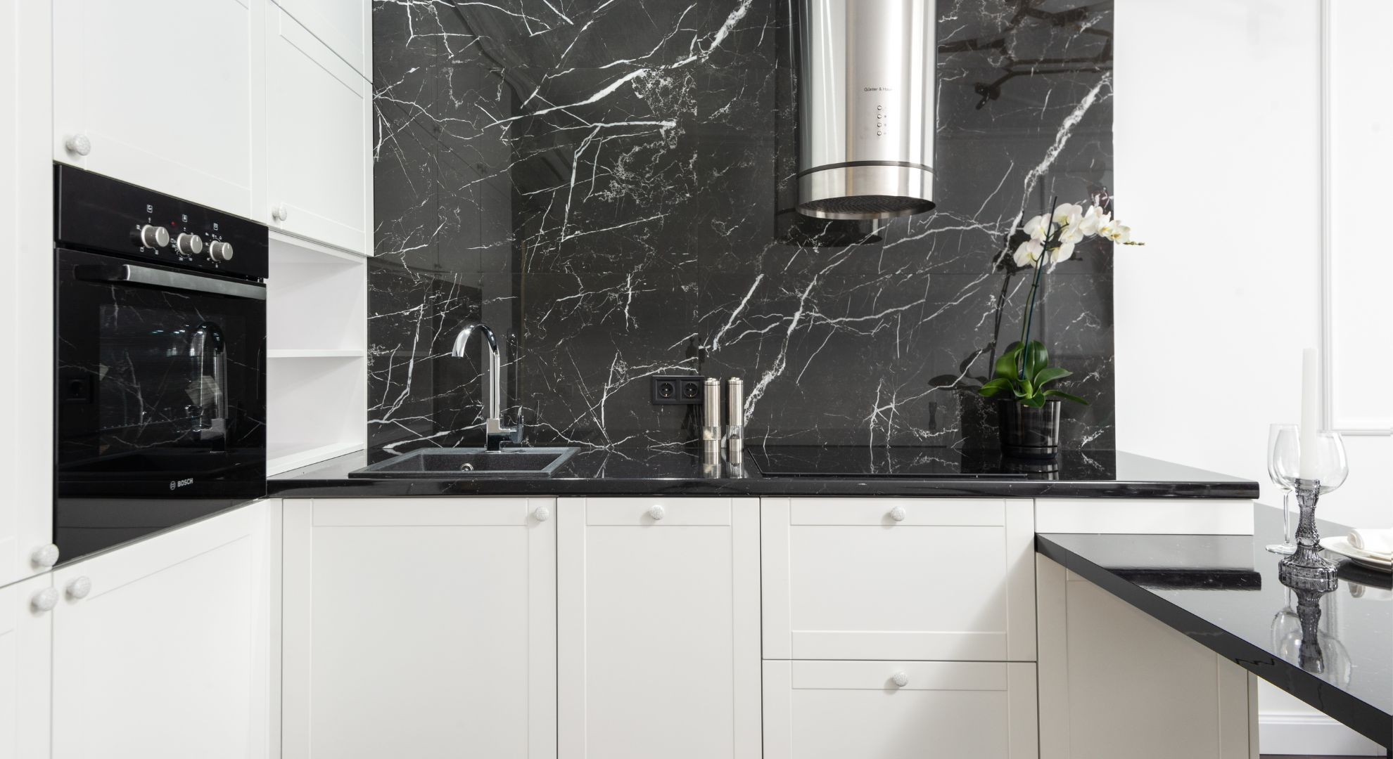 white kitchen cabinets with striking black marble backsplash