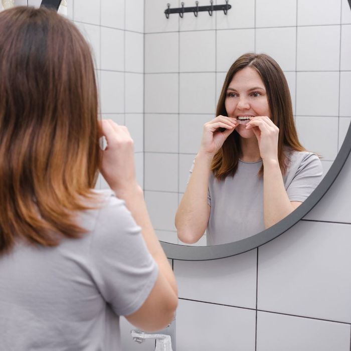 woman putting on Invisalign in mirror