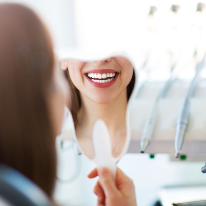 woman looking at her smile in the mirror