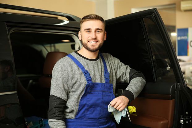 Smiling worker standing near car in shop_ Window tinting service.jpg