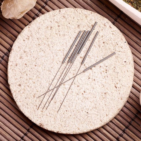 Acupuncture needles laying on a stone