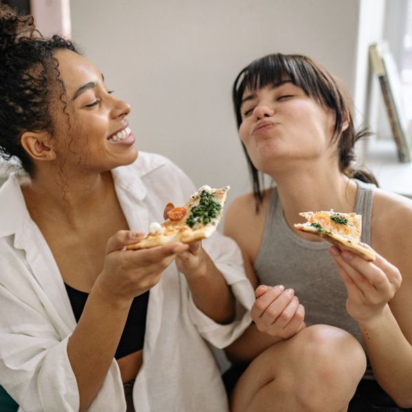 two smiling woman eating pizza