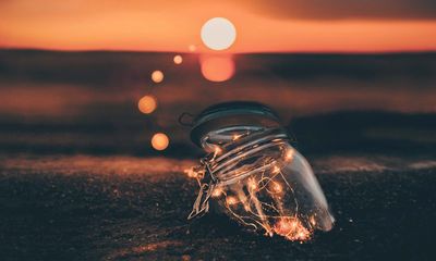 A glass jar with lights in it during sunset 