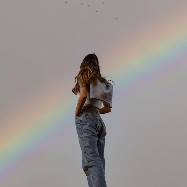 woman standing under rainbow