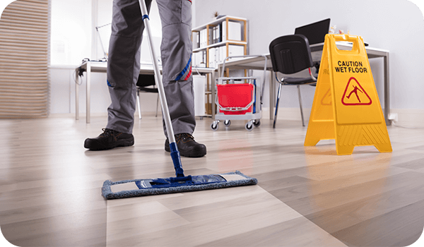 Man mopping wood floor in office setting