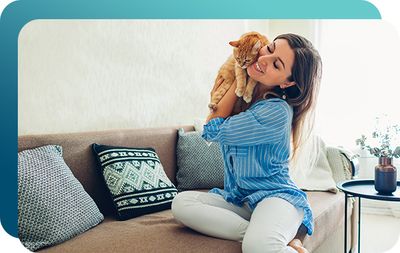 Woman holding her pet cat while sitting on tan couch
