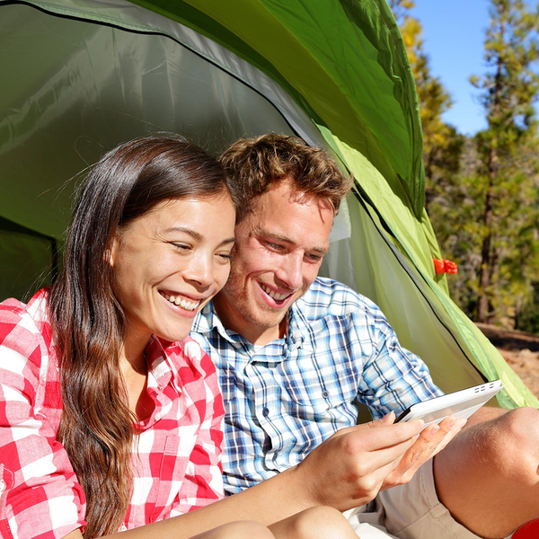 Happy couple looking at a tablet while camping