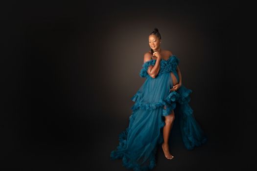 Expecting mother in a flowing blue gown posing in a fine art studio maternity session, photographed by Kelly Saxon Photography in Christiana TN Fine Art Maternity Photography Murfreesboro TN Kelly Saxon Photography