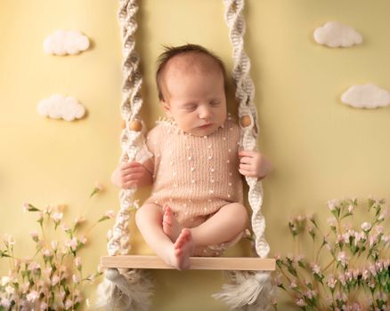 Newborn baby sleeping on a swing with floral accents and yellow background, photographed by Kelly Saxon Photography in Murfreesboro Tennessee Newborn Swing Photo - Kelly Saxon Photography