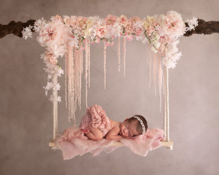 Newborn baby girl posed on a floral swing with soft pink flowers, photographed by Kelly Saxon Photography in Christiana TN Floral Swing Newborn Photography Murfreesboro TN Kelly Saxon Photography