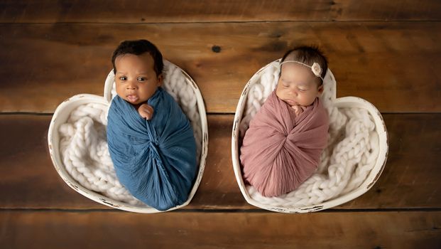 Twinn newborn babies wrapped in pink and blue swaddles posed in heart-shaped bowls, photographed by Kelly Saxon Photography in Murfreesboro, Tennessee. Twin Newborn Photography - Kelly Saxon Photography