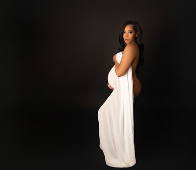 Expecting mother in a white gown drape during a fine art maternity boudoir session by Kelly Saxon Photography, professional maternity and boudoir photographer in Murfreesboro, Tennessee. Maternity Boudoir Portrait in White - Kelly Saxon Photography