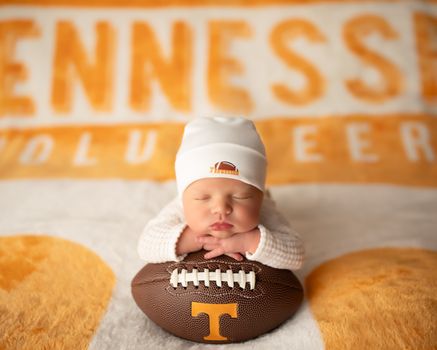 Newborn baby posed with a Tennessee Volunteers football and hat on a orange blanket, photographed by Kelly Saxon Photography in Christiana TN Tennessee Volunteers Newborn Photography Murfreesboro TN Kelly Saxon Photography
