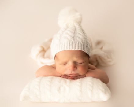 Peacefu newborn baby boy sleeping on a soft white blanket wearing a knit hat during a professional studio newborn photography session in Murfressboro, Tennessee. Newborn Boy Photography in Murfreesboro TN