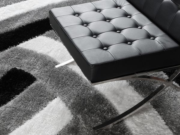 An image of a black leather chair on top of a newly cleaned and spotless rug with black, white, and grey intersecting lines. 