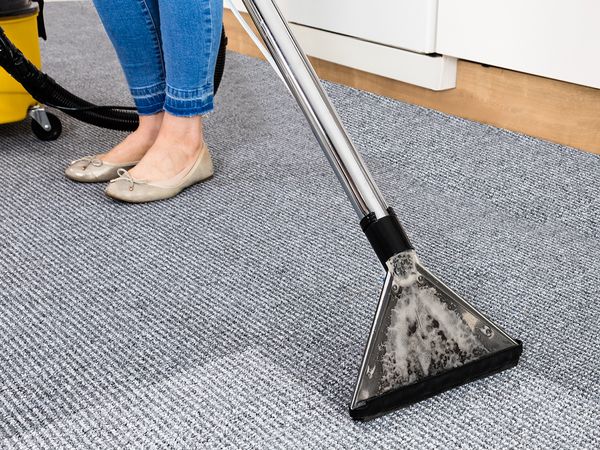 A woman cleans carpeting in an office building.