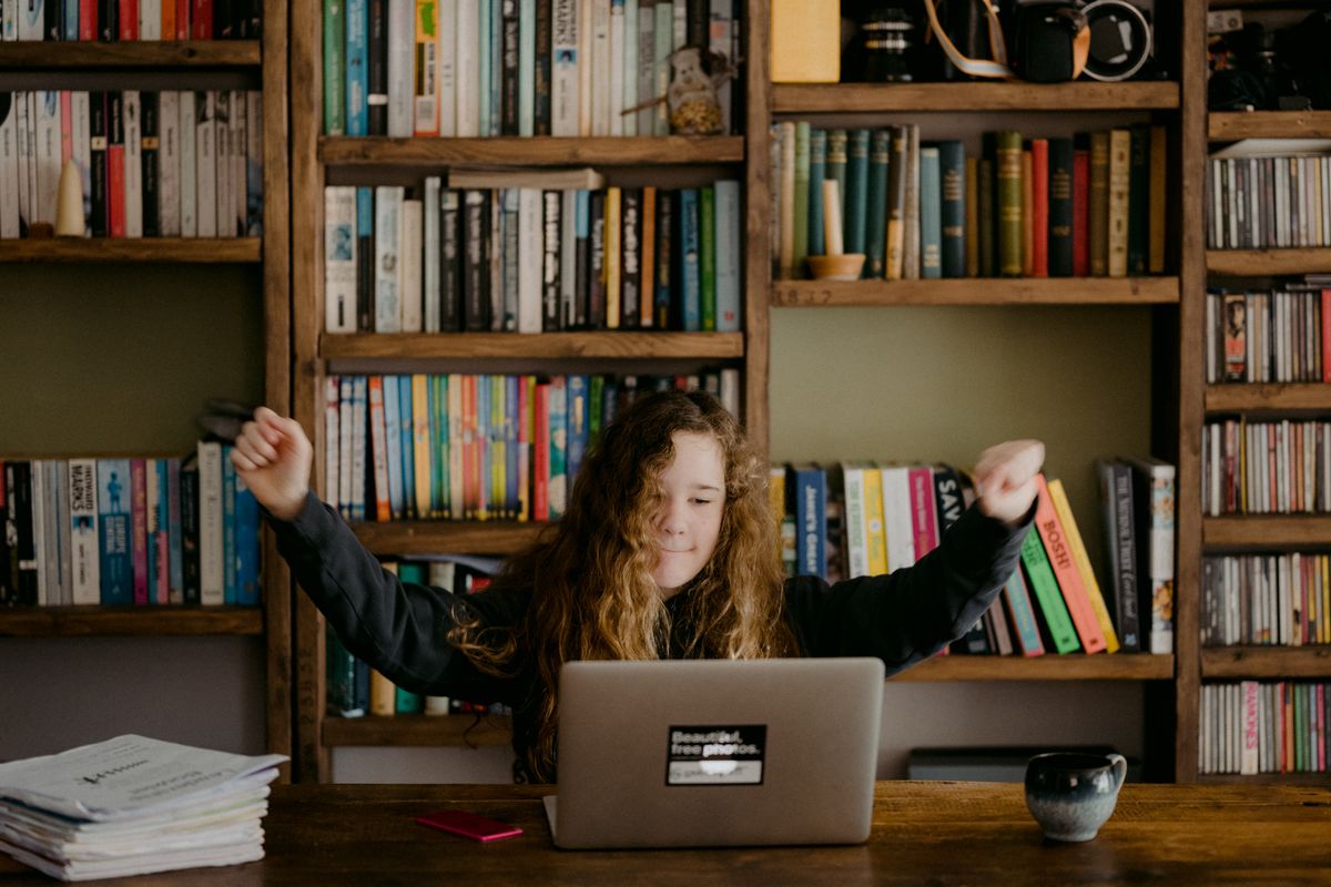 young woman celebrating at laptop