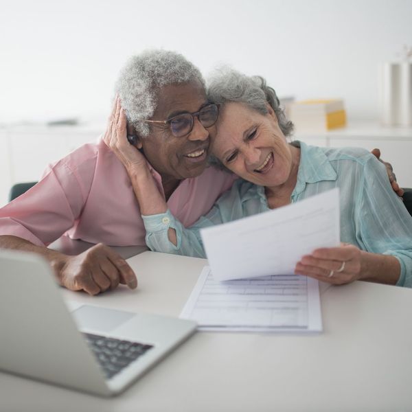 happy older couple embracing over paperwork happy older couple embracing over paperwork