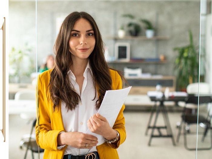 Office employee wearing a yellow blazer and holding documents