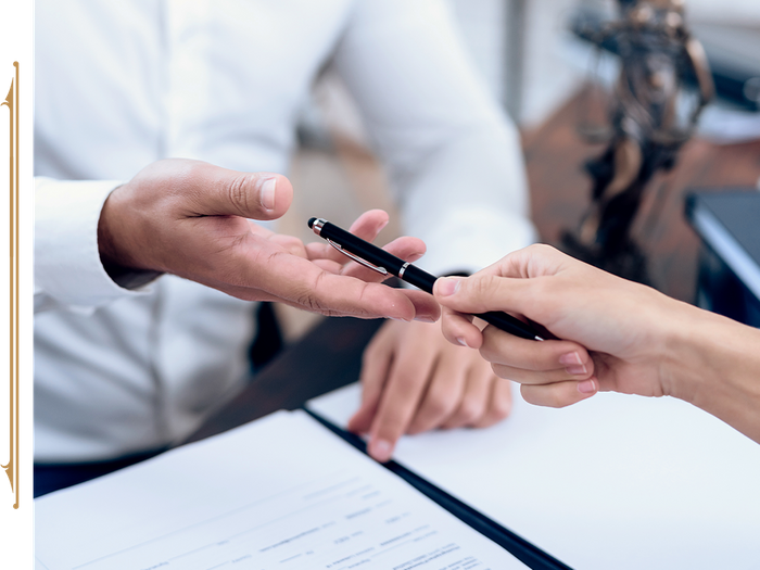 Lawyer handing a man a pen to sign a document