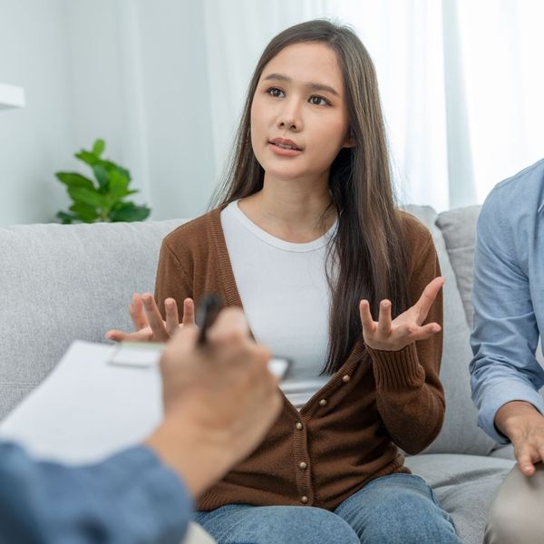 Therapist takes notes on a clipboard, while talking to an employee