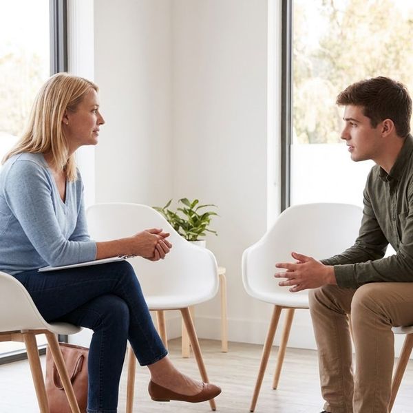 A compassionate female therapist listens intently to a young man during an authentic counseling session.