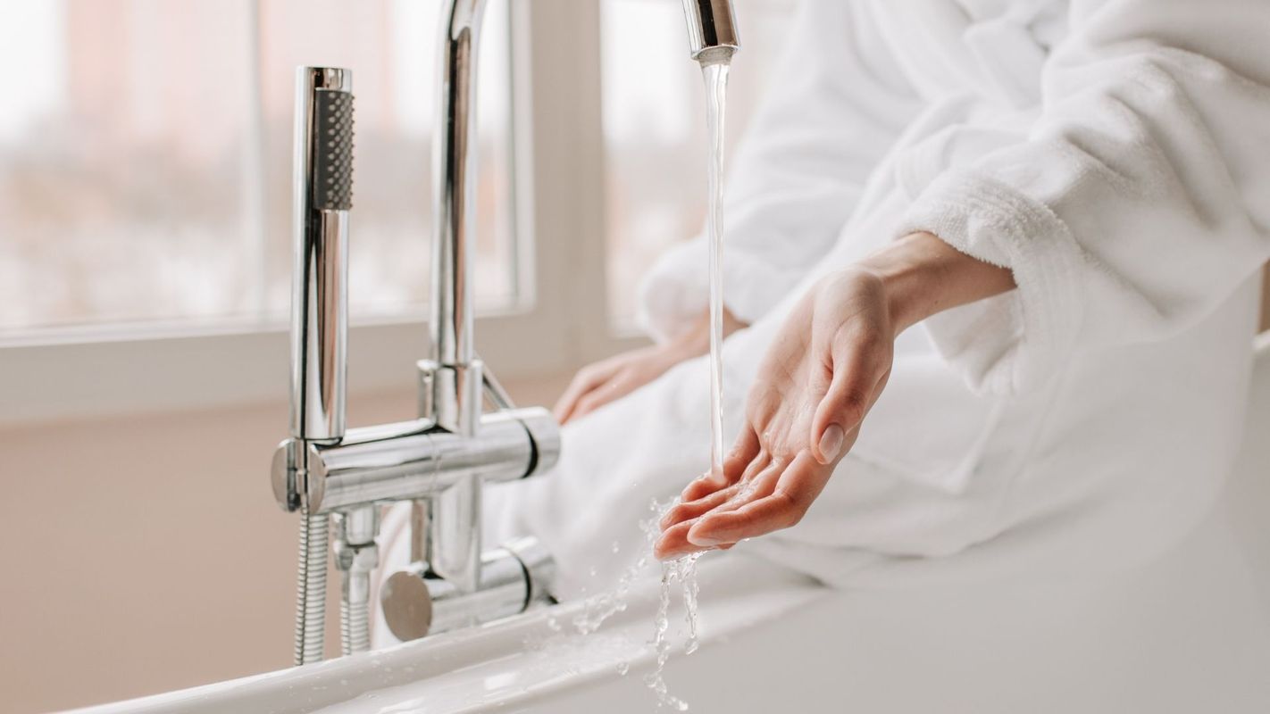 A woman feeling the water temp before a bath