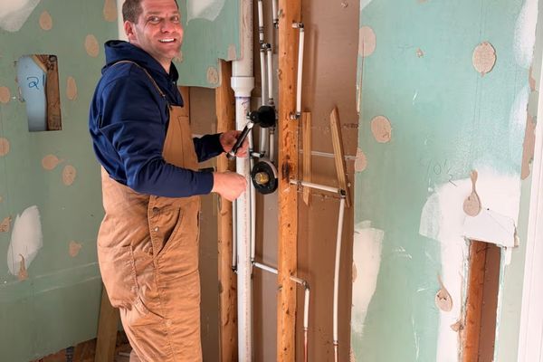 Employee repairing pipes in a residential wall