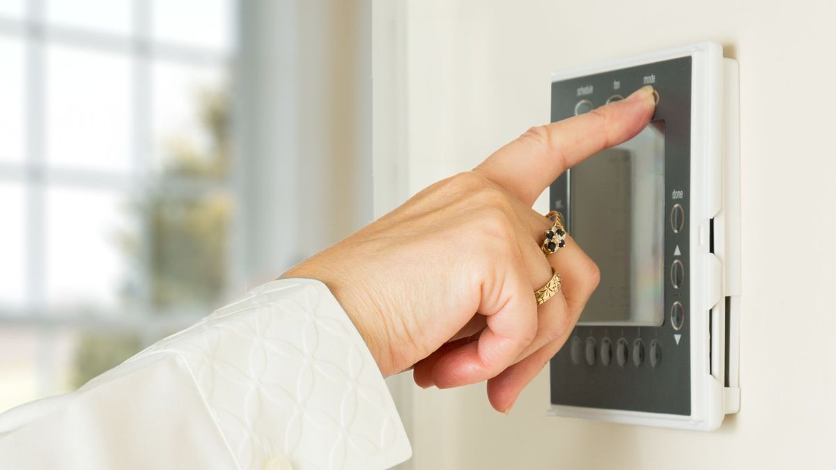 Image of a woman adjusting a thermostat