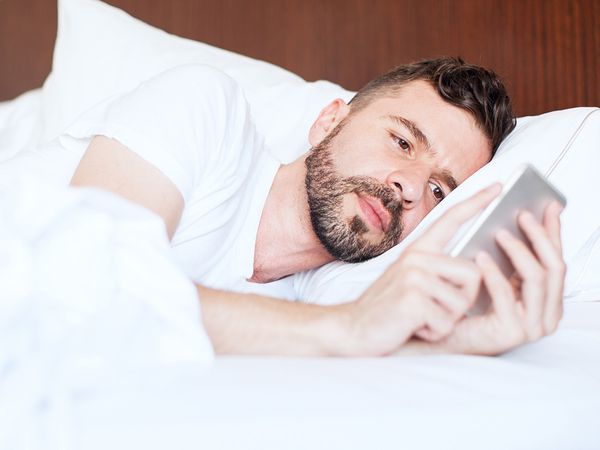 Man having a hard time falling asleep in a hotel bed