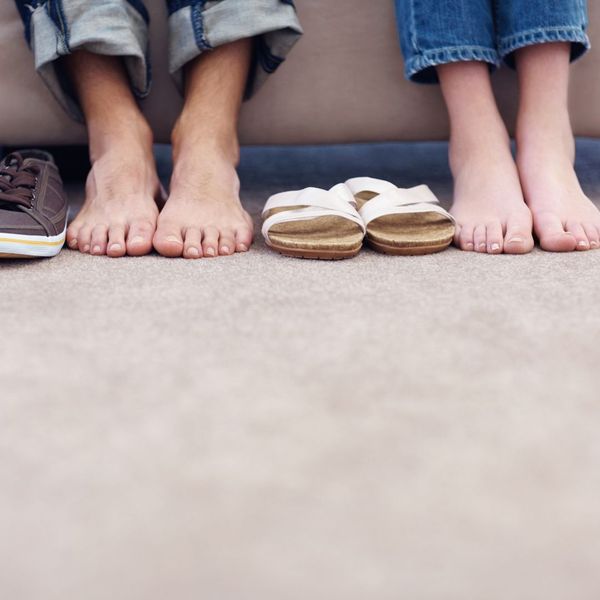 Two people with their shoes off resting on carpet. 