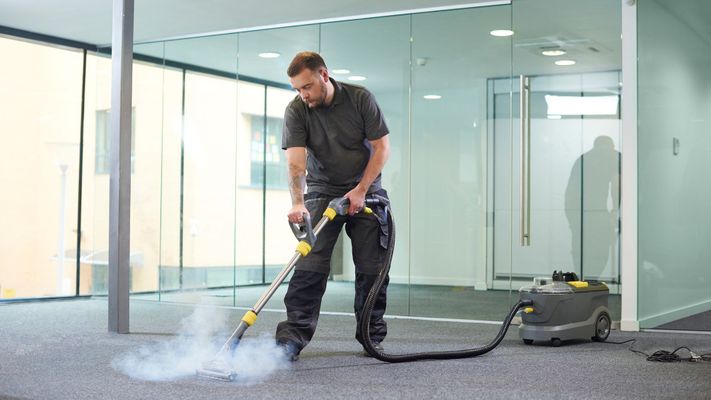 Man using a carpet steamer to clean carpet. 