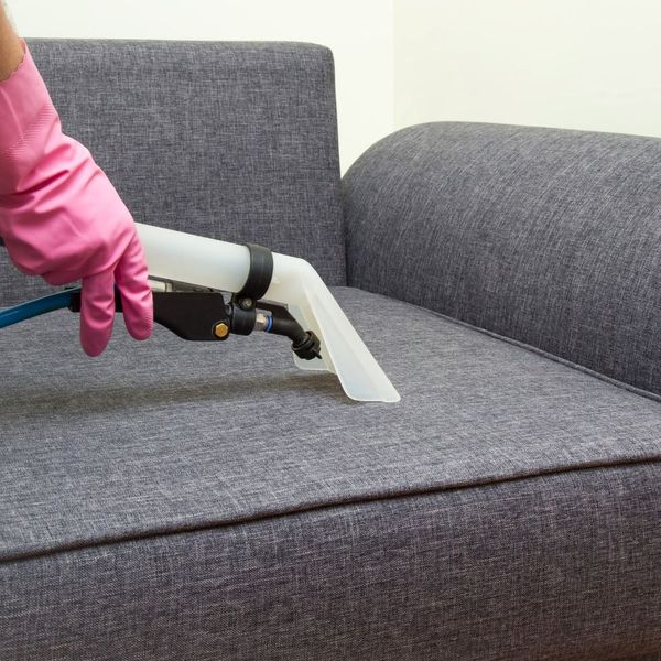 Person using professional equipment to clean a couch. 