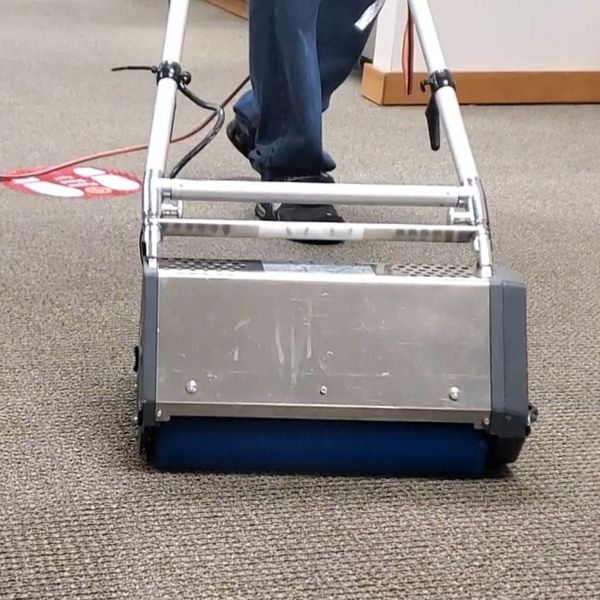 A professional-grade carpet agitation machine deep cleans and lifts the pile of a beige carpet.