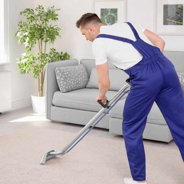 Man professionally cleaning a carpet. 